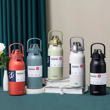 Five 1700ml stainless steel thermos bottles in red, blue, green, white, and black, displayed upright with handles and flip-top lids on a teal table