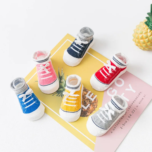 Colorful 3D shoe-style anti-slip baby socks with silicone grip soles, displayed in pink, red, yellow, blue, gray, and navy for toddlers and infants