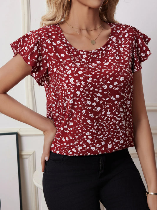 Woman wearing red boho floral chiffon blouse with butterfly sleeves and pleated hem, styled with black pants for casual summer fashion.