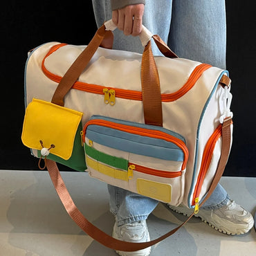 Unisex multi-purpose nylon duffel bag in white with colorful pockets and orange zippers, carried by hand with crossbody strap and sporty sneakers