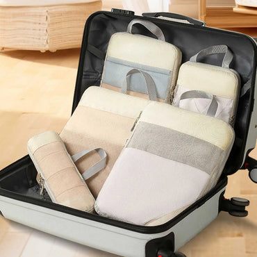 Set of multicolor compression packing cubes neatly packed in an open suitcase, showing organized travel storage with mesh panels and handles