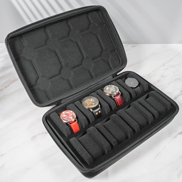 Open black 8-slot watch case with four assorted wristwatches on a marble surface