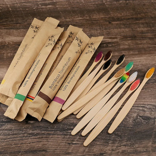 Set of eco-friendly bamboo toothbrushes with colorful bristles and biodegradable paper packaging, displayed on wooden surface BeTrendy