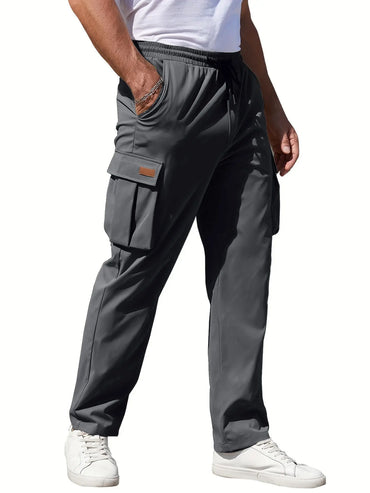 Man wearing gray loose fit cargo pants with flap pockets and drawstring waist, styled with a white tee and white sneakers for modern casual wear.