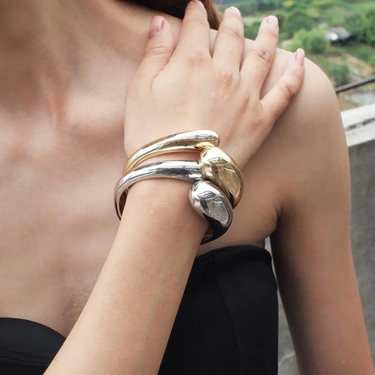 Woman wearing a bold mixed color alloy cuff bracelet by MANILAI featuring gold and silver tones with a modern geometric design