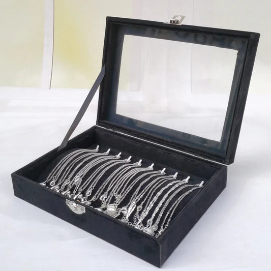 Elegant silver necklaces neatly arranged in a black velvet jewelry display box with a transparent glass lid