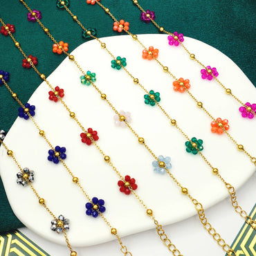 Bright multicolor boho flower charm bracelets displayed in rows on a white tray with a green velvet background.