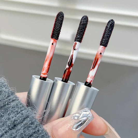 Close-up of three XMSJ Waterproof Peel-Off Lip Tint applicators in matte silver tubes with deep red tint, held in hand with nail art BeTrendy
