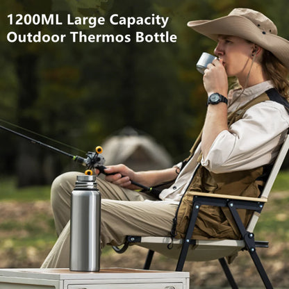 Man drinking from 1200ML stainless steel outdoor thermos bottle while fishing and camping – large capacity insulated travel flask. BeTrendy