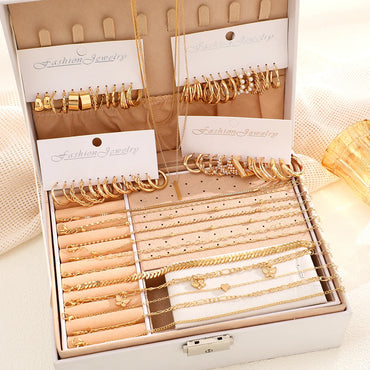 Complete gold jewelry set displayed in a white gift box featuring necklaces, hoop earrings, and gold chain anklets.  Boho BeTrendy