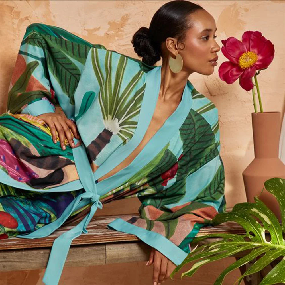Woman lounging in bohemian tropical kimono with Obi-style sash and wide sleeves
