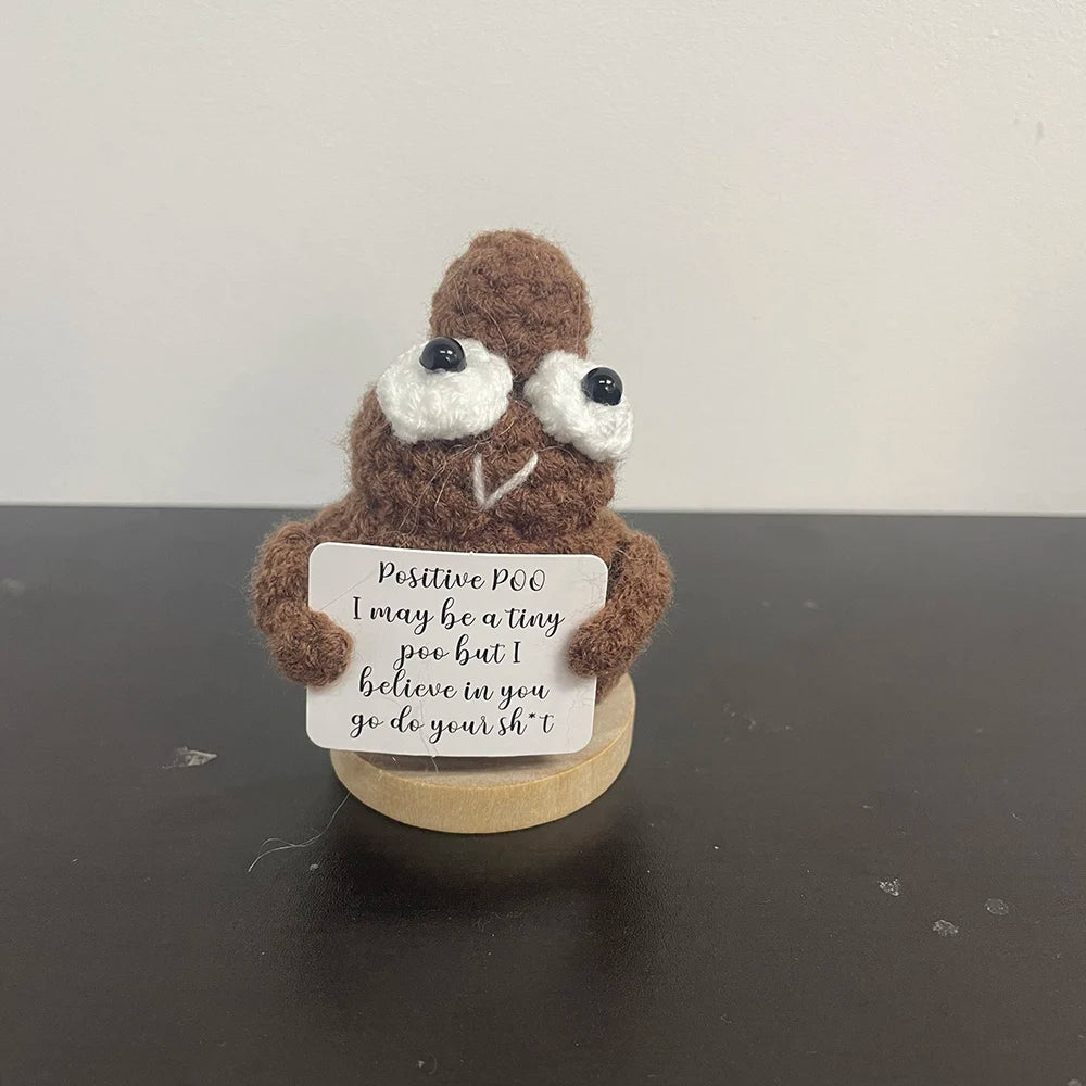 Handmade crochet poop emoji-style doll holding a sign that says "Positive poo – I may be a tiny poo but I believe in you, go do your sh*t!