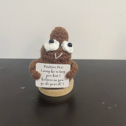 Handmade crochet poop emoji-style doll holding a sign that says "Positive poo – I may be a tiny poo but I believe in you, go do your sh*t!