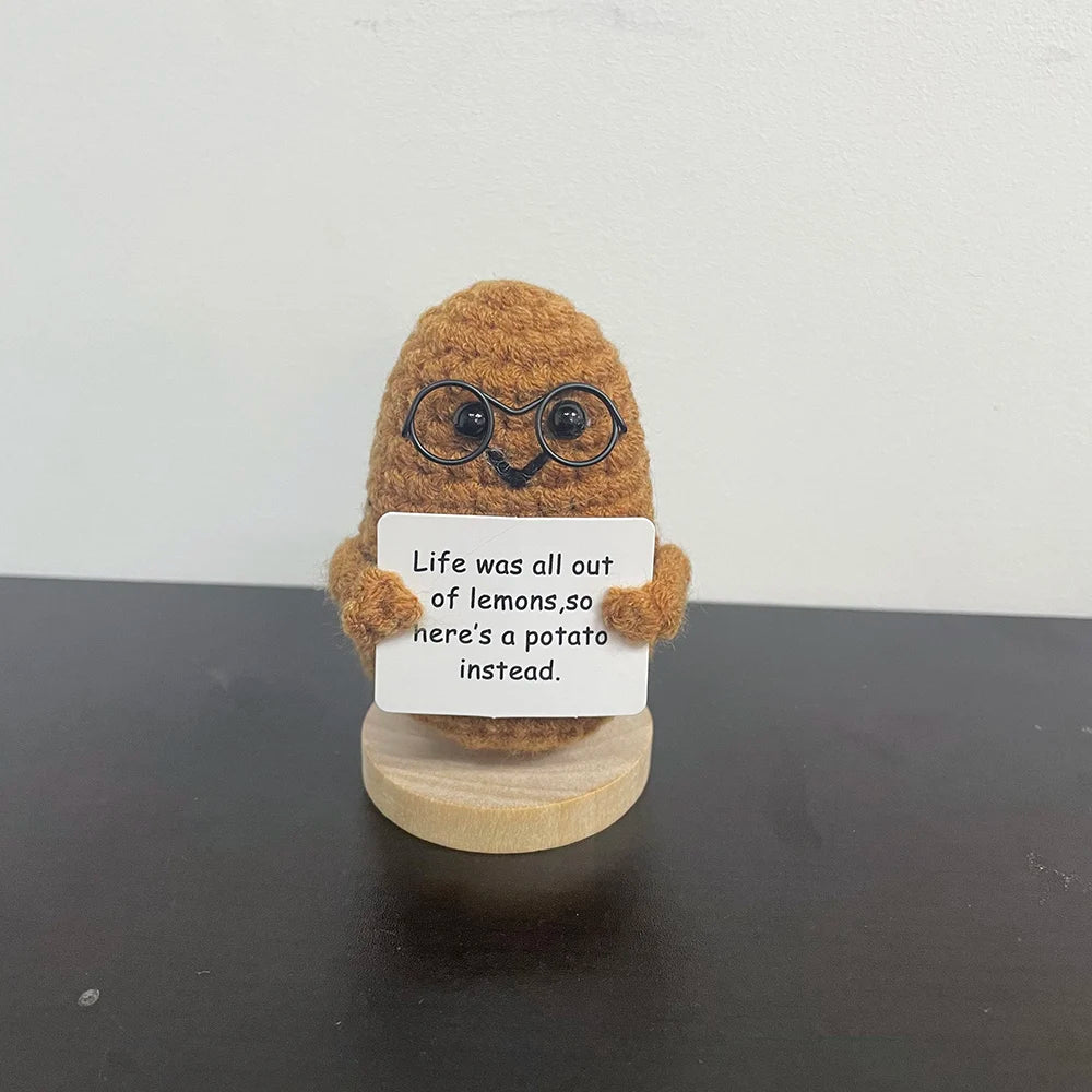 Handmade crochet potato plush doll wearing glasses, holding a sign that says "Life was all out of lemons, so here’s a potato instead