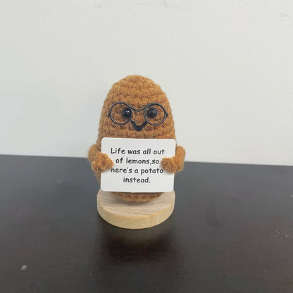 Handmade crochet potato plush doll wearing glasses, holding a sign that says "Life was all out of lemons, so here’s a potato instead