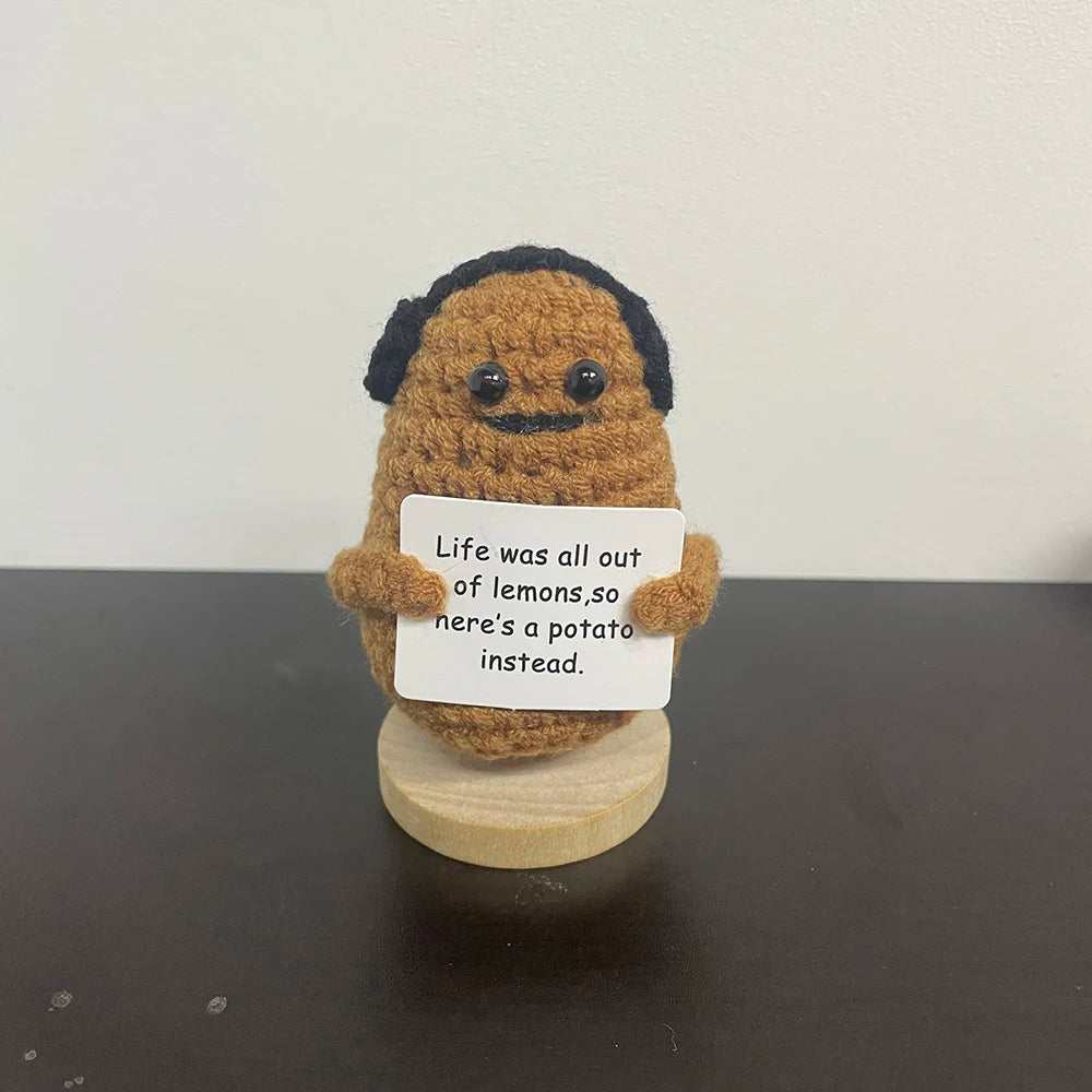 Handmade crochet potato plush doll with black mustache and hair, holding a sign that says "Life was all out of lemons, so here’s a potato instead