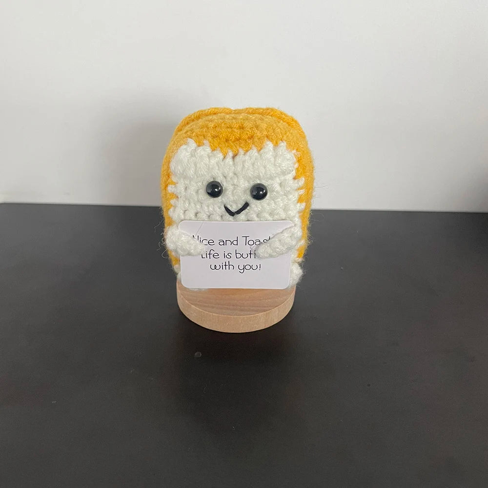 Handmade crochet toast plush doll with smiling face, holding a sign that says "Nice and toasty – Life is butter with you!