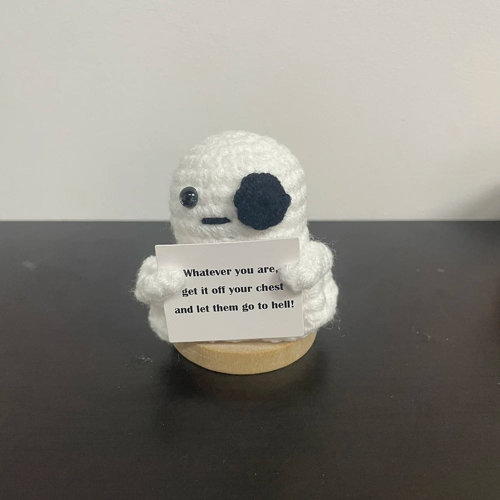 Crochet ghost plush with black eye patch holding sign that says 'Whatever you are, get it off your chest and let them go to hell!' — quirky desk decor gift