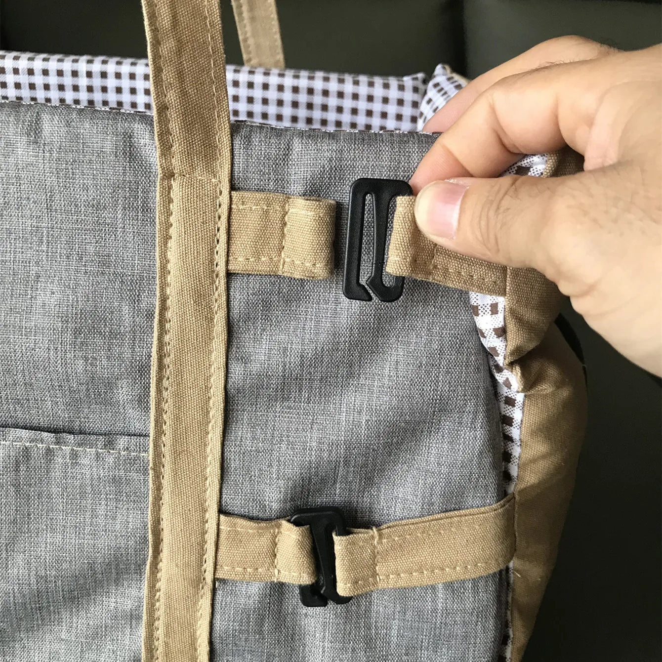 Close-up of safety buckle and adjustable strap on the dog car seat for secure attachment.