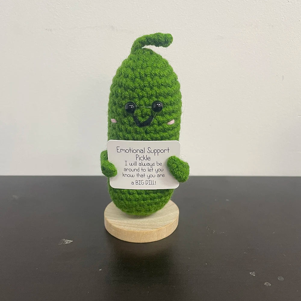 Handmade crochet pickle plush doll with a smiling face and pink cheeks, holding a sign that says "Emotional Support Pickle – I will always be around to let you know that you are a BIG DILL!"