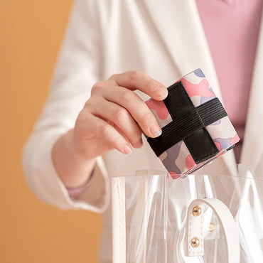 Woman placing a folded pink camouflage Oxford shopping bag into a clear handbag, showcasing its compact and portable design.  BeTrendy