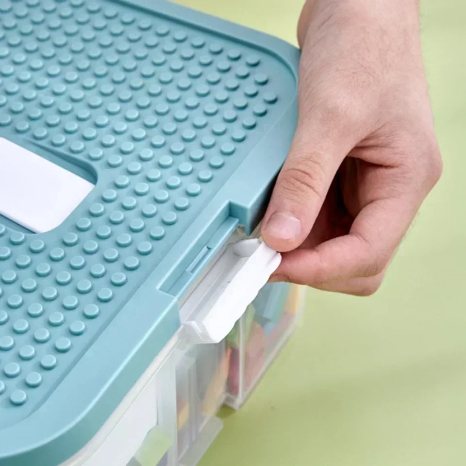 Close-up of hand locking the lid of a Lego-compatible storage box with snap-on clip for secure closure and safe transport