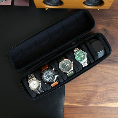 Long black zippered watch case open to show five different wristwatches securely placed in foam slots on a wooden surface