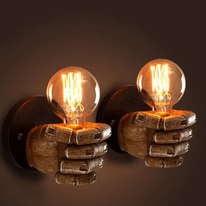 Pair of Nordic resin hand wall lamps featuring left and right fists gripping round Edison bulbs, mounted side-by-side on a dark wall with warm glow