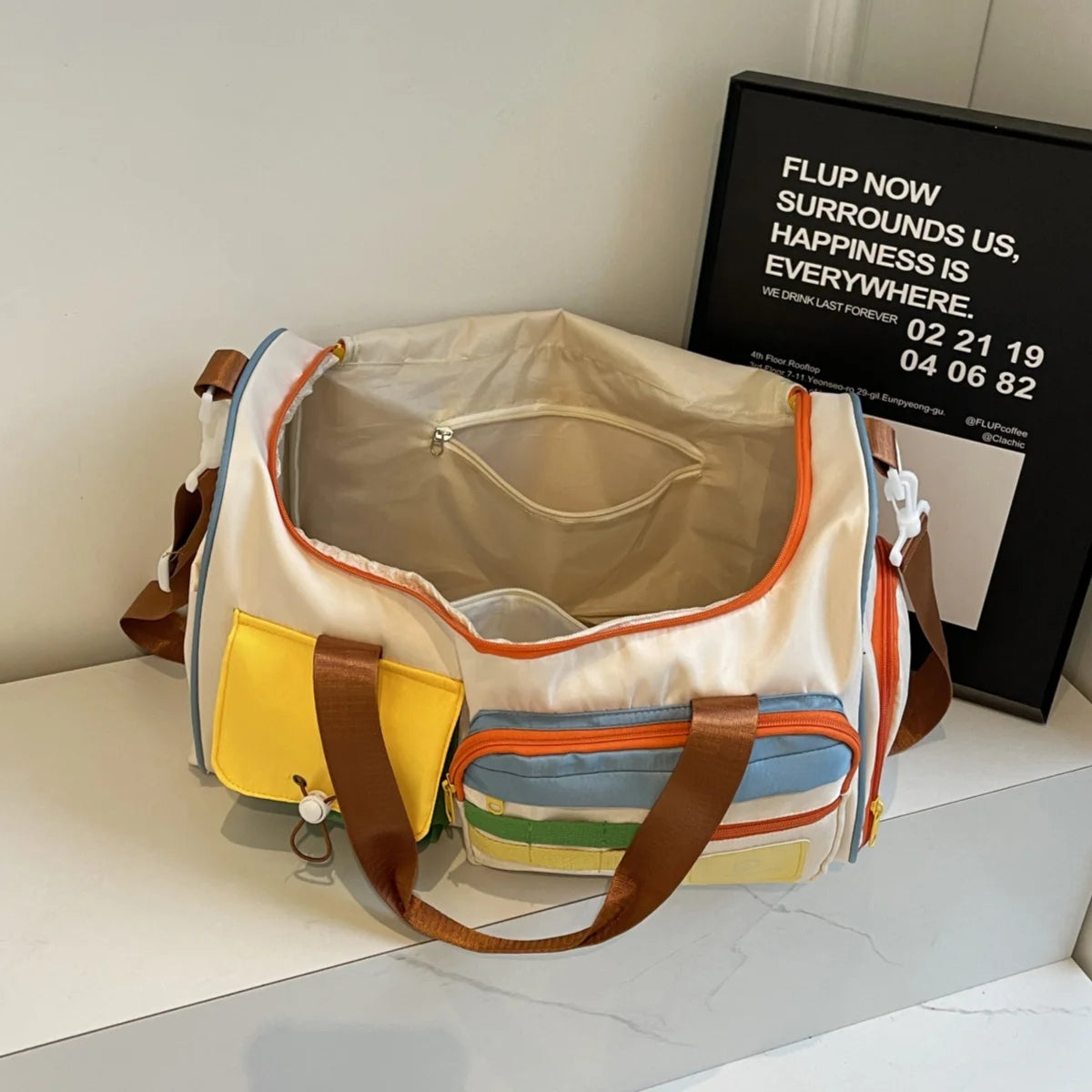 Top view of an open nylon duffel bag with interior mesh pocket and spacious main compartment, featuring colorful exterior pockets and orange zipper