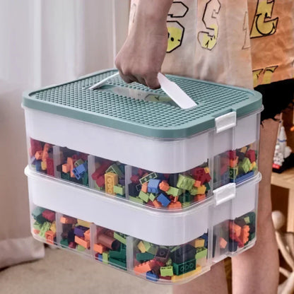 Person holding double-layer Lego-compatible storage box by handle, filled with colorful building blocks and secured with side clips
