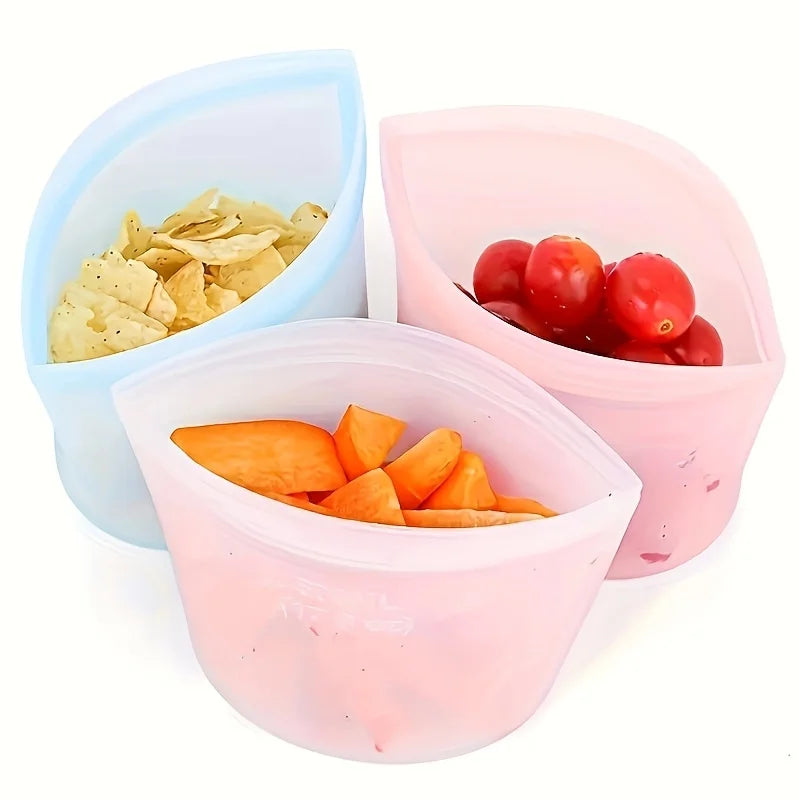 Three reusable silicone food storage bags filled with chips, cherry tomatoes, and sliced fruit—perfect for snacks, freezer use, or meal prep